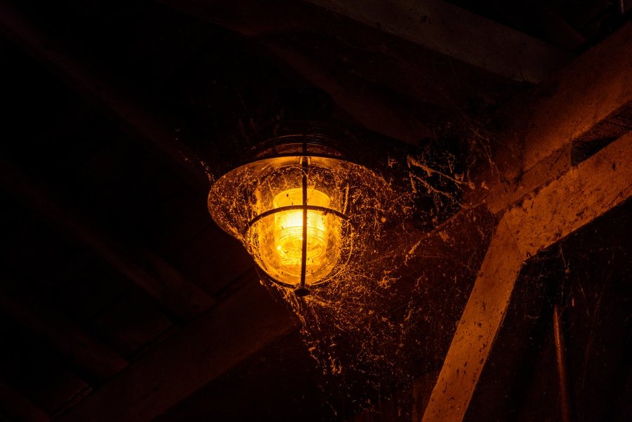 Une lanterne allumée sous une charpente, la nuit