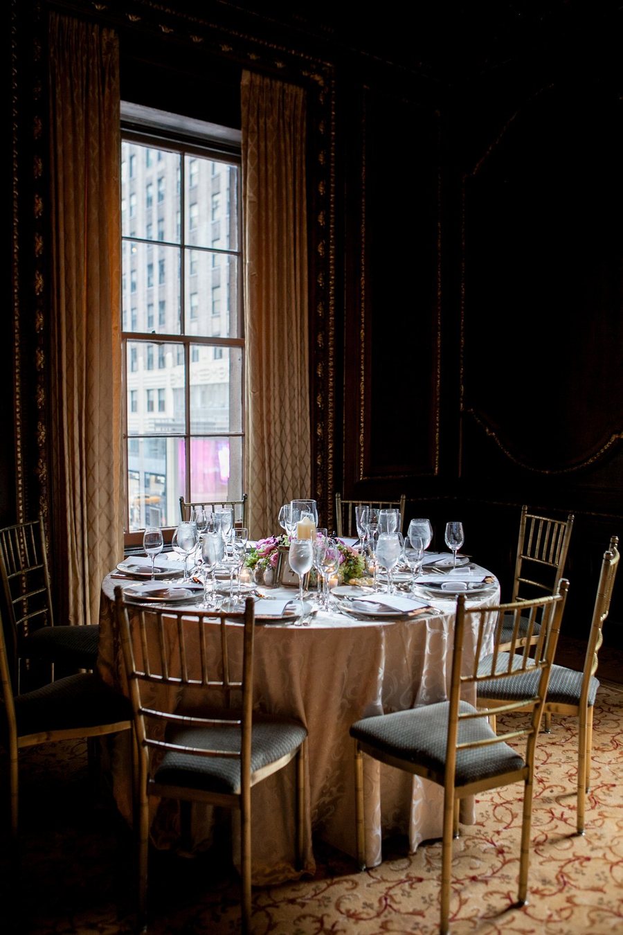 Une table ronde dressée dans une salle aux rideaux sombres